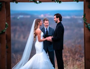 Wedding photography of beautiful couple under a wooden arch giving their vows